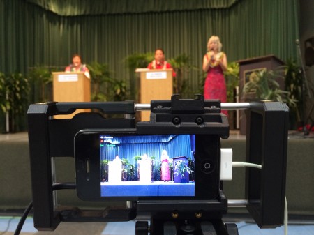 An iPhone 4 in a BeastGrip tripod mount, audio from the board coming in on the left, external power supply coming in on the right, video streaming live on Ustream. This was at the Senate candidates debate in Hilo, Hawaii. Photo by Baron Sekiya